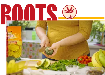 Woman preparing fresh vegetables and avocado in a kitchen with Mayte plantain chips nearby