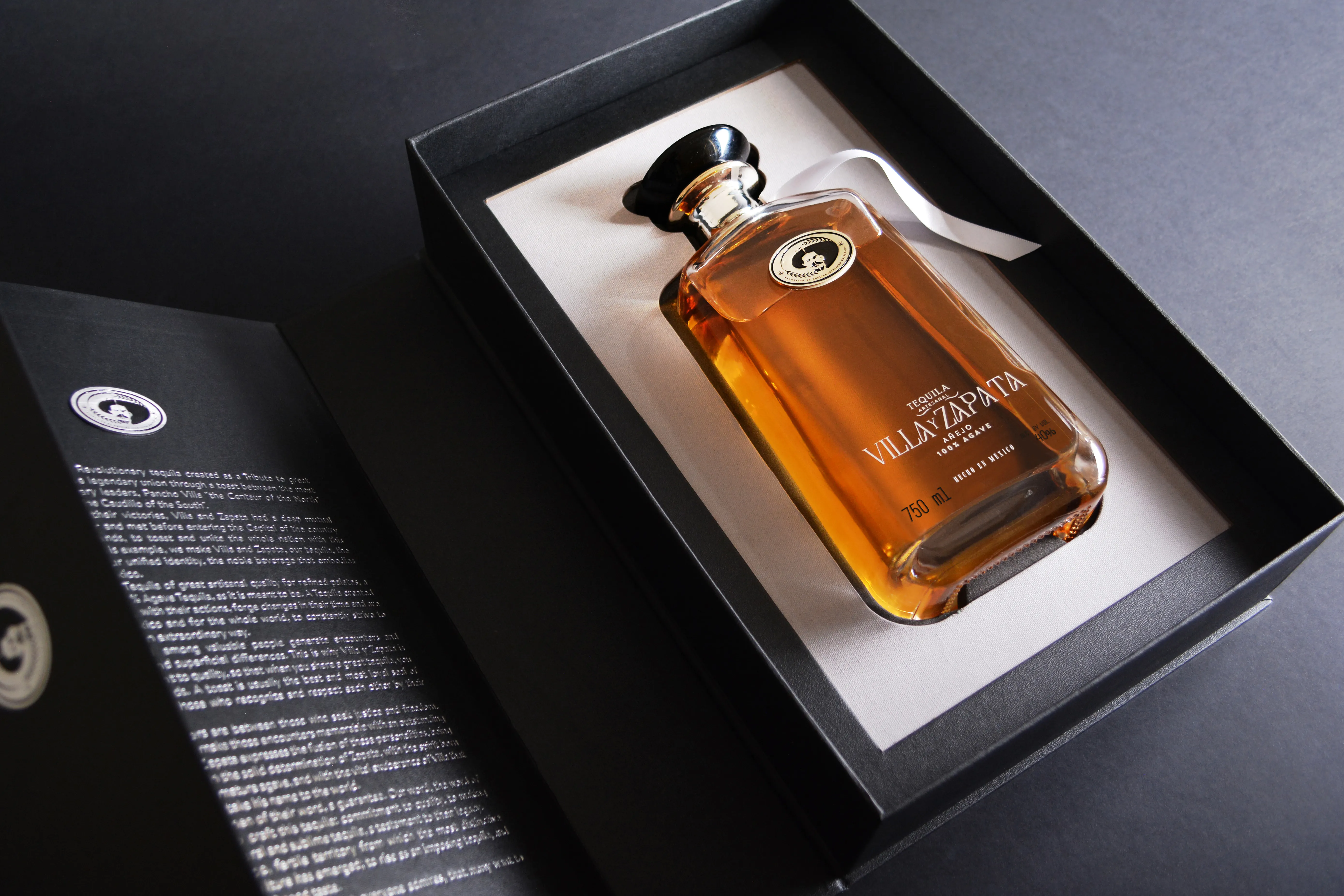 Añejo bottle in open black gift box with brand story booklet