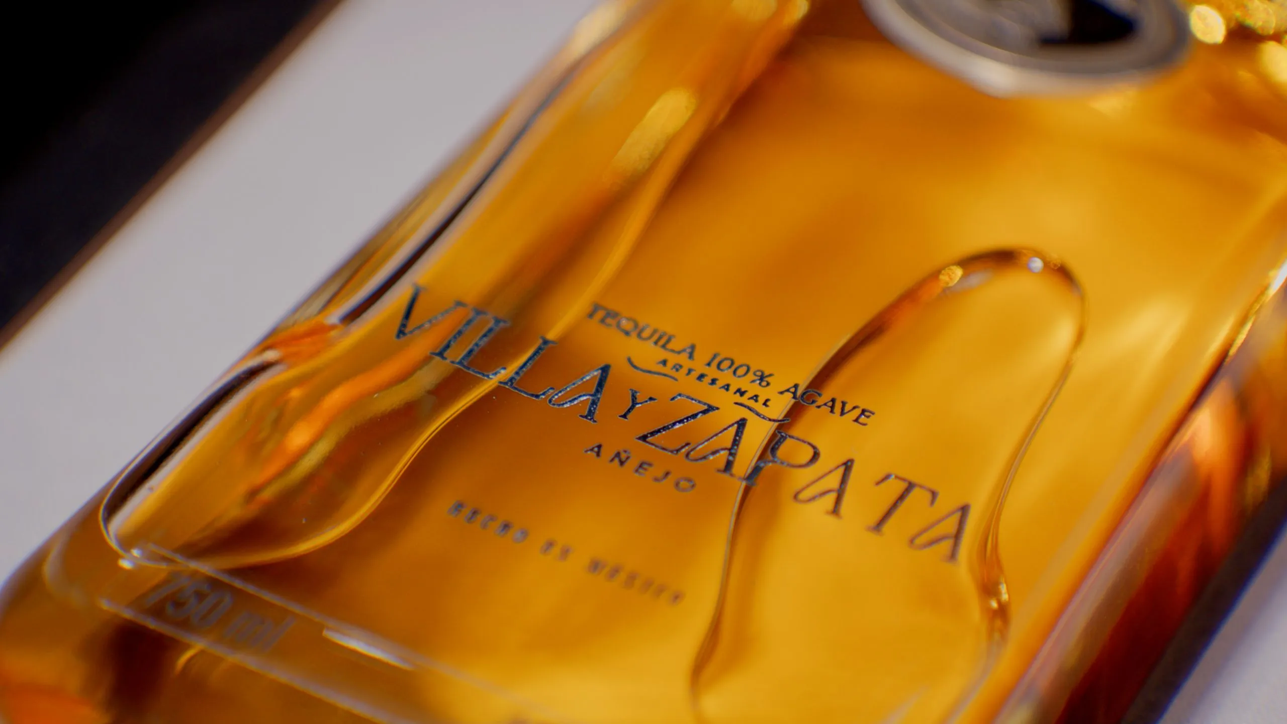 Añejo bottle embossed glass label close-up showing amber tequila