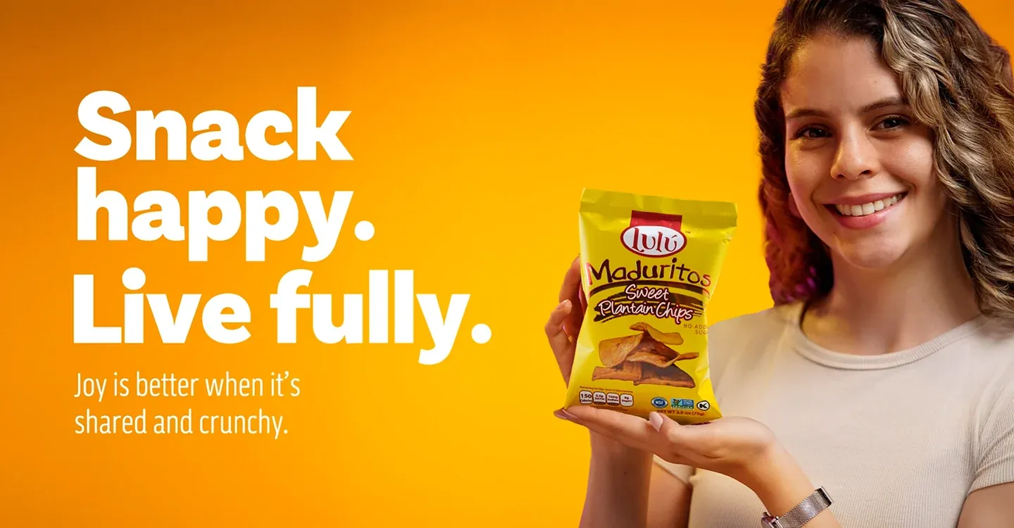 Woman on orange background holding LuLu Maduritos bag with tagline Snack happy Live fully