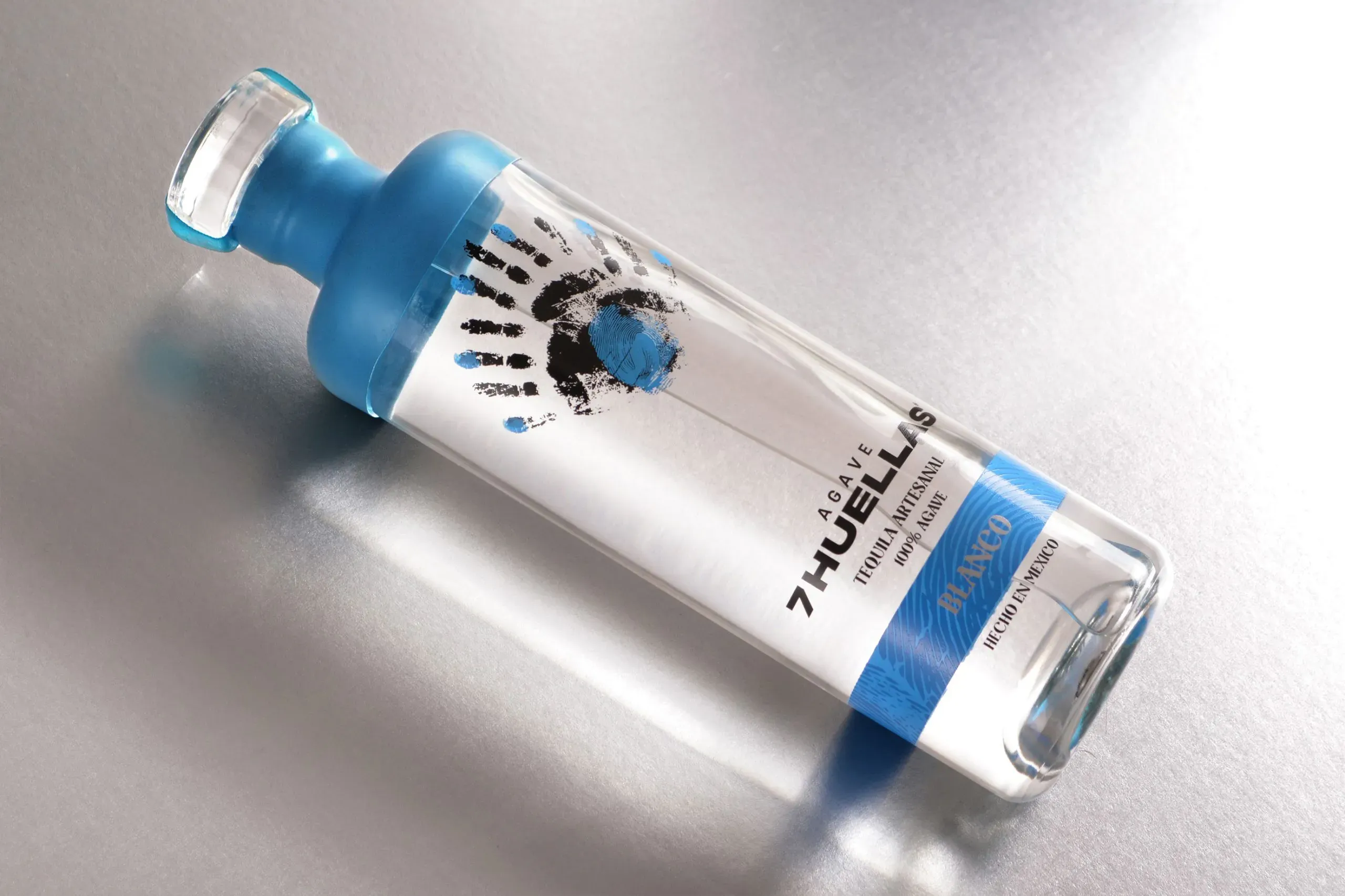 Blanco bottle lying on its side, overhead on metallic surface