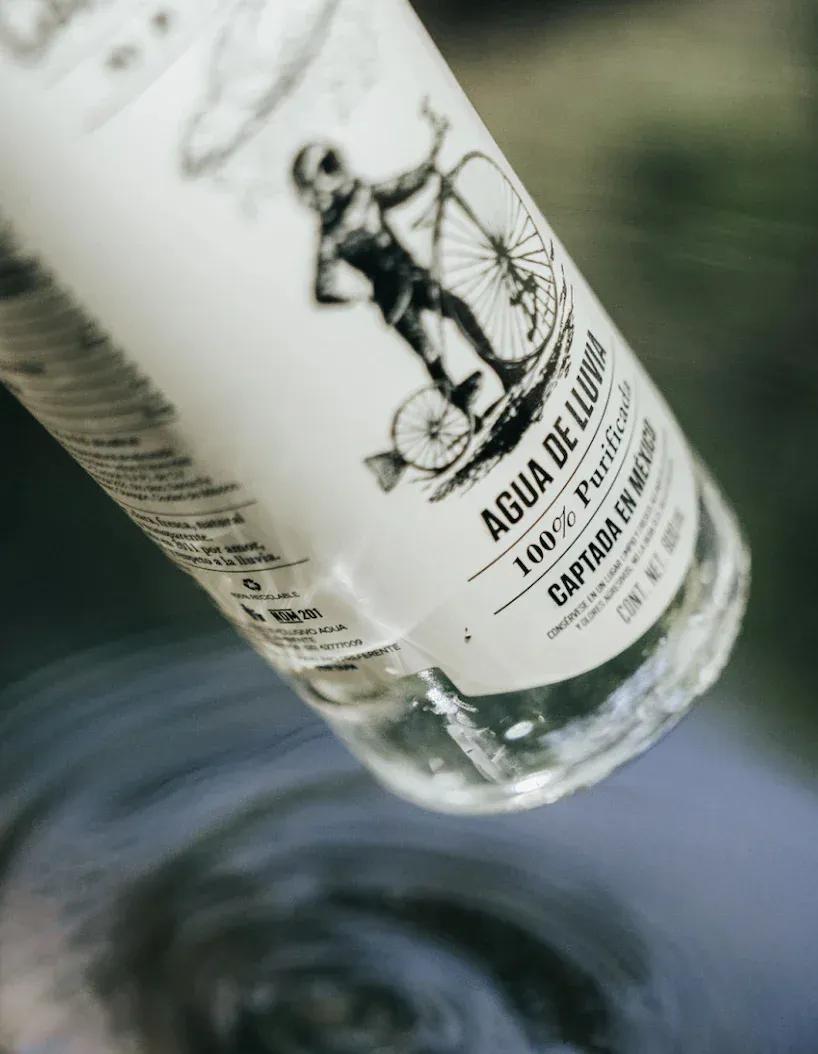Close-up of Casa del Agua bottle label reading Agua de Lluvia reflected over water surface