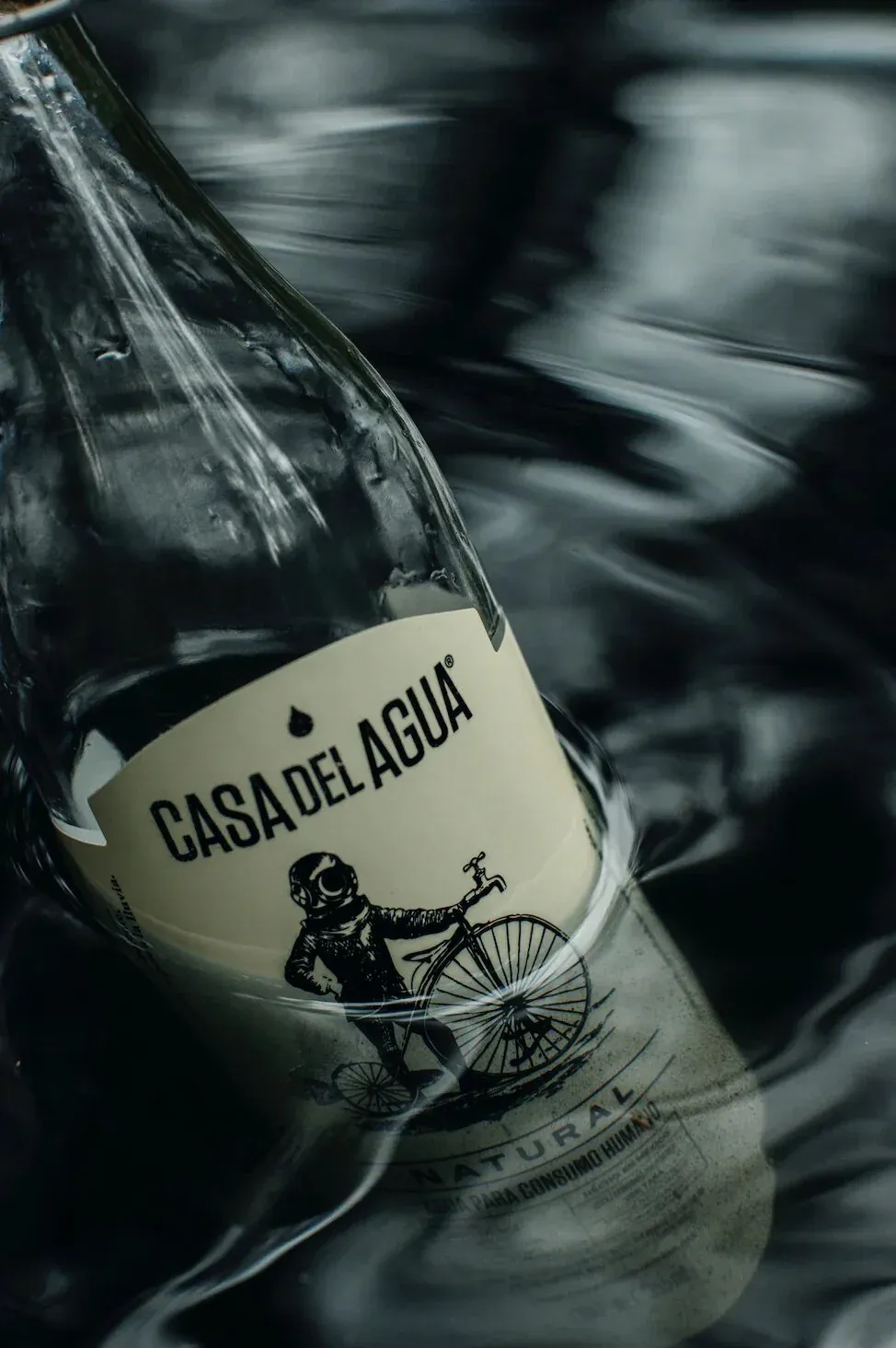 Casa del Agua bottle partially submerged in dark water with label visible