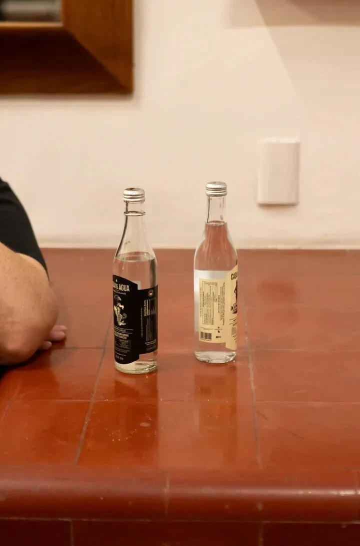 Natural and sparkling Casa del Agua bottles side by side on a terracotta tile counter