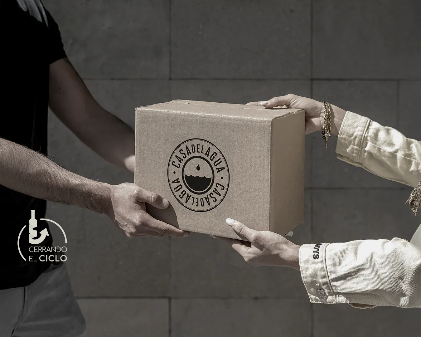 Person handing over a branded Casa del Agua delivery box with Cerrando el Ciclo sustainability badge