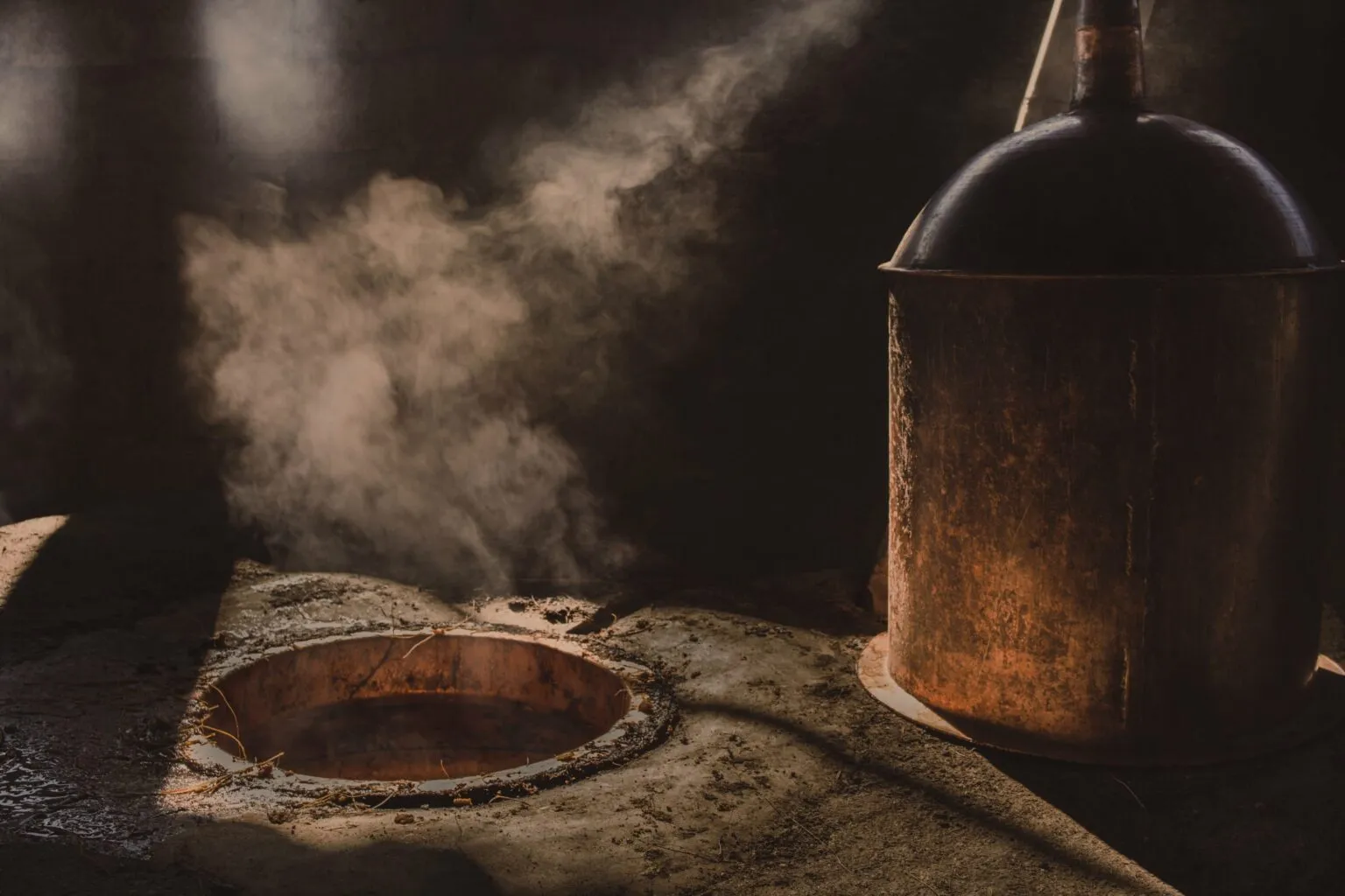 Copper still with steam rising from distillation pot at mezcal palenque