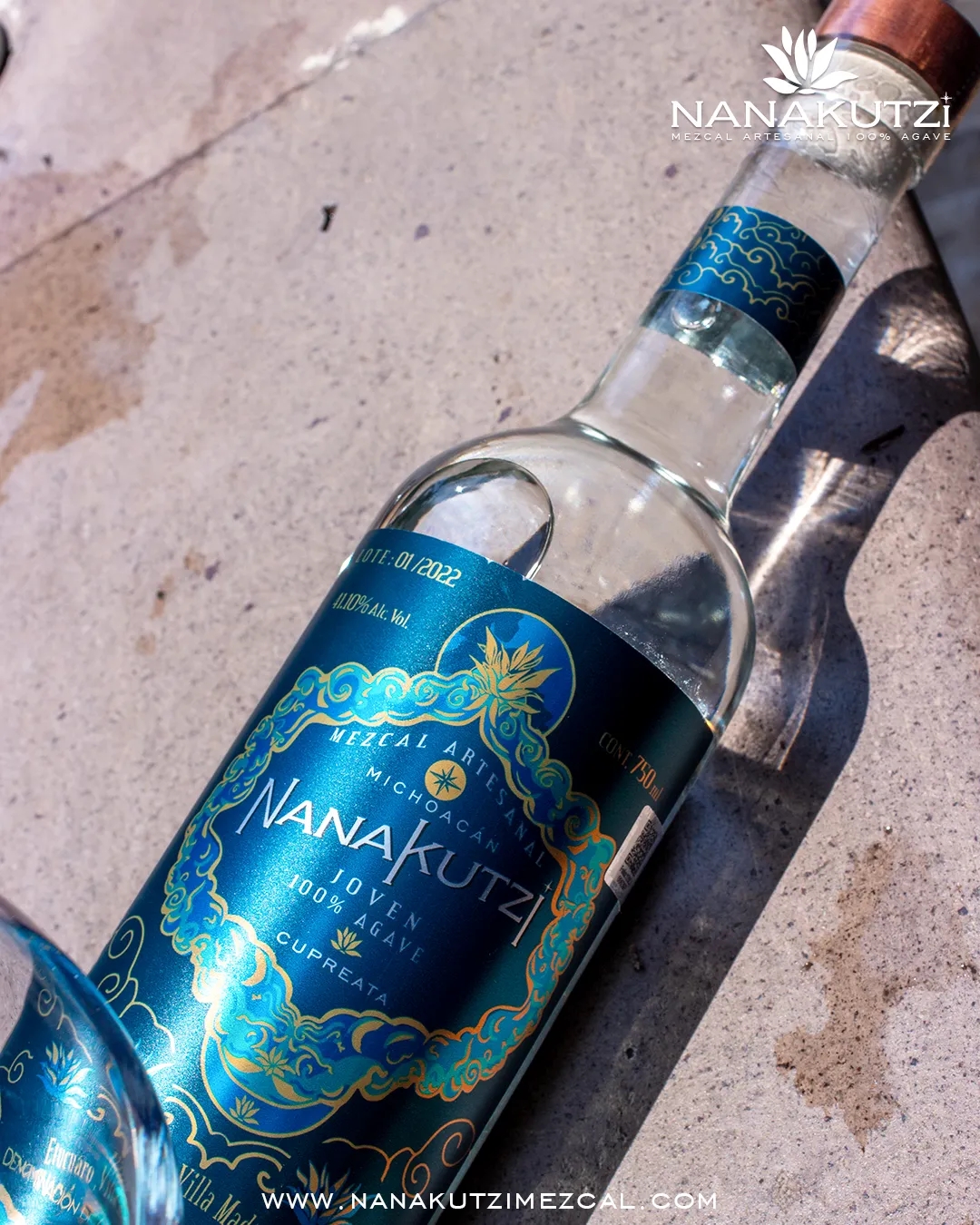 Two Nanakutzi Cupreata bottles with blue-gold labels on concrete surface