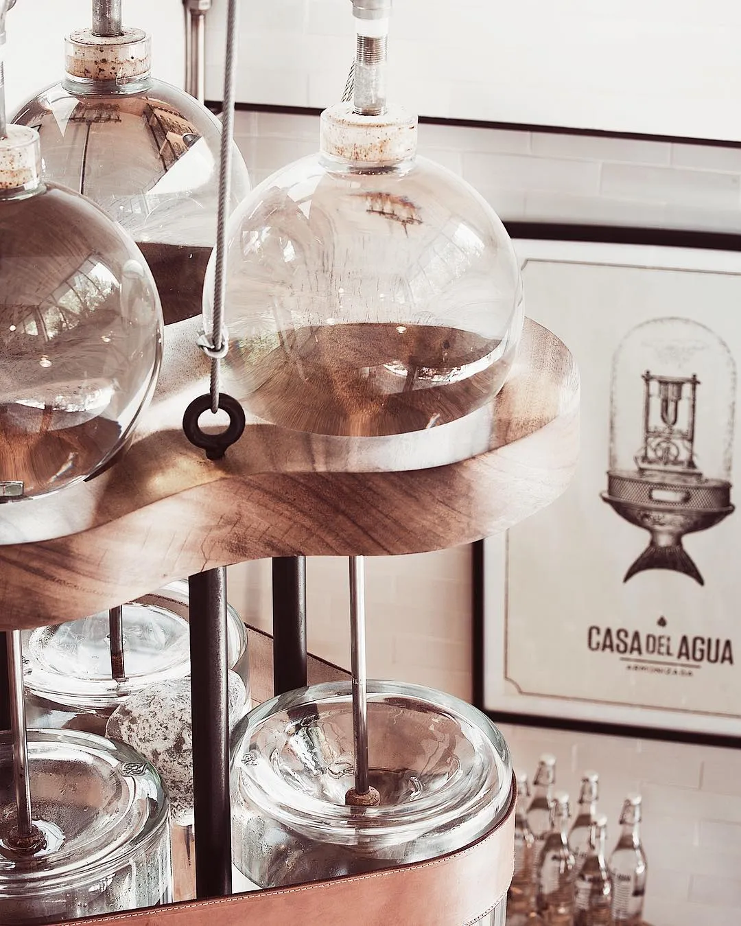 Glass water dispensers displayed on wooden shelf in Casa del Agua showroom with brand signage