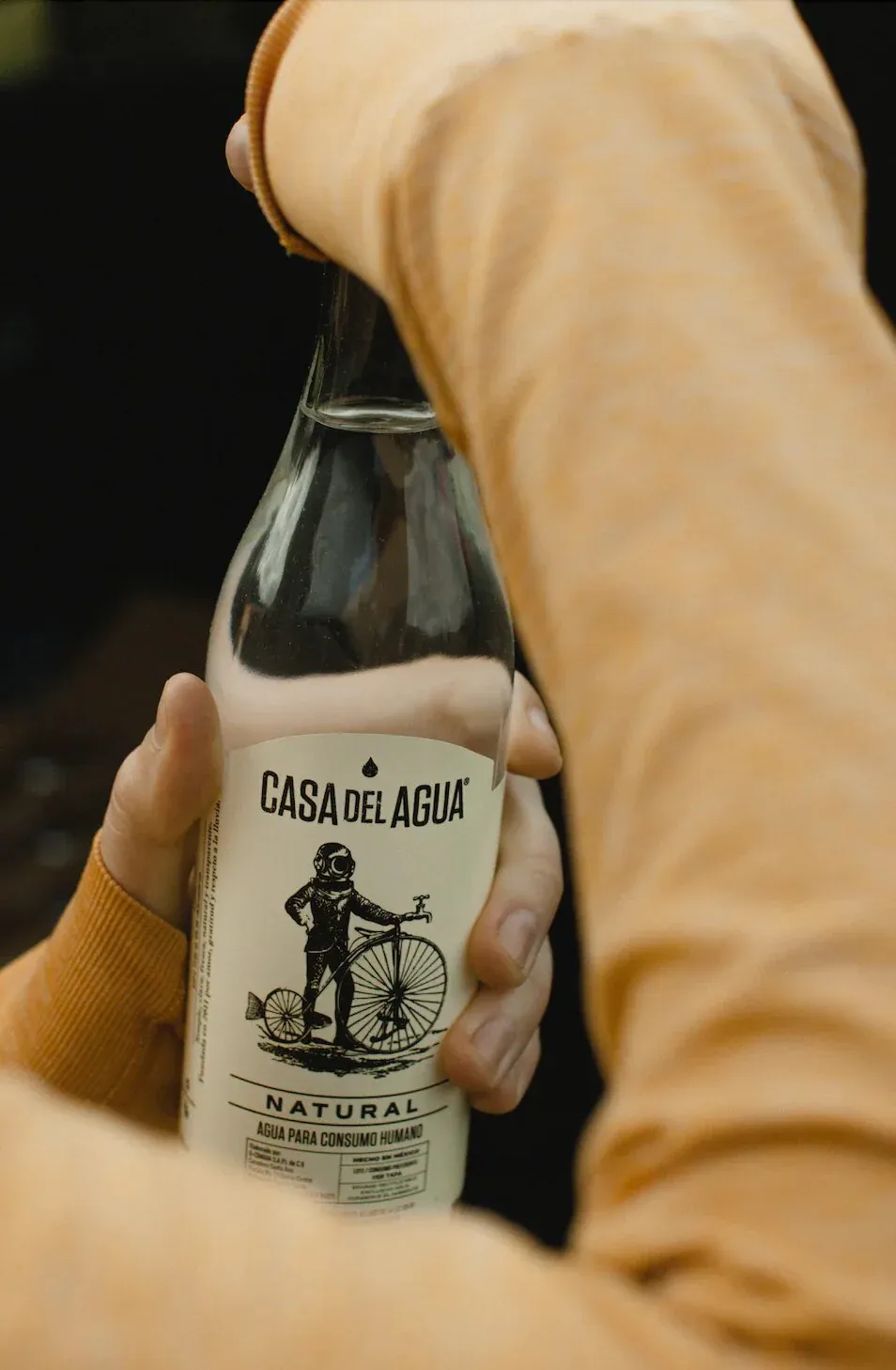 Close-up of a hand holding a Casa del Agua Natural rainwater bottle