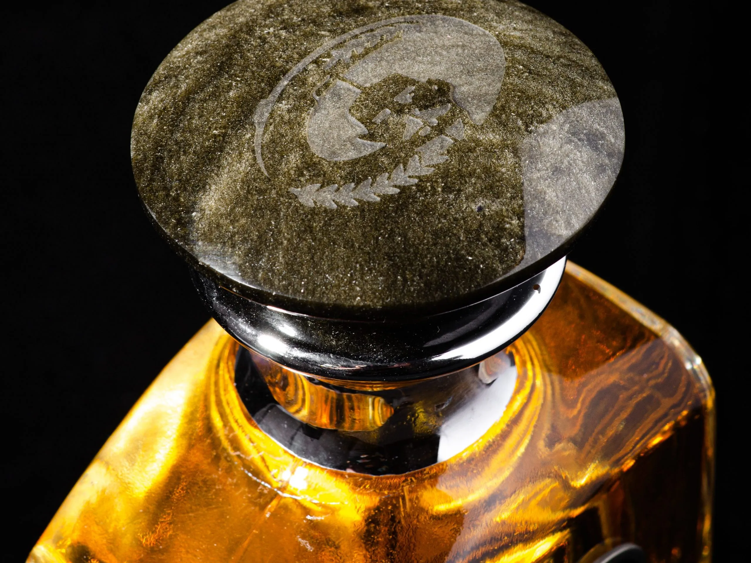 Añejo bottle obsidian cap close-up with eagle emblem on black background