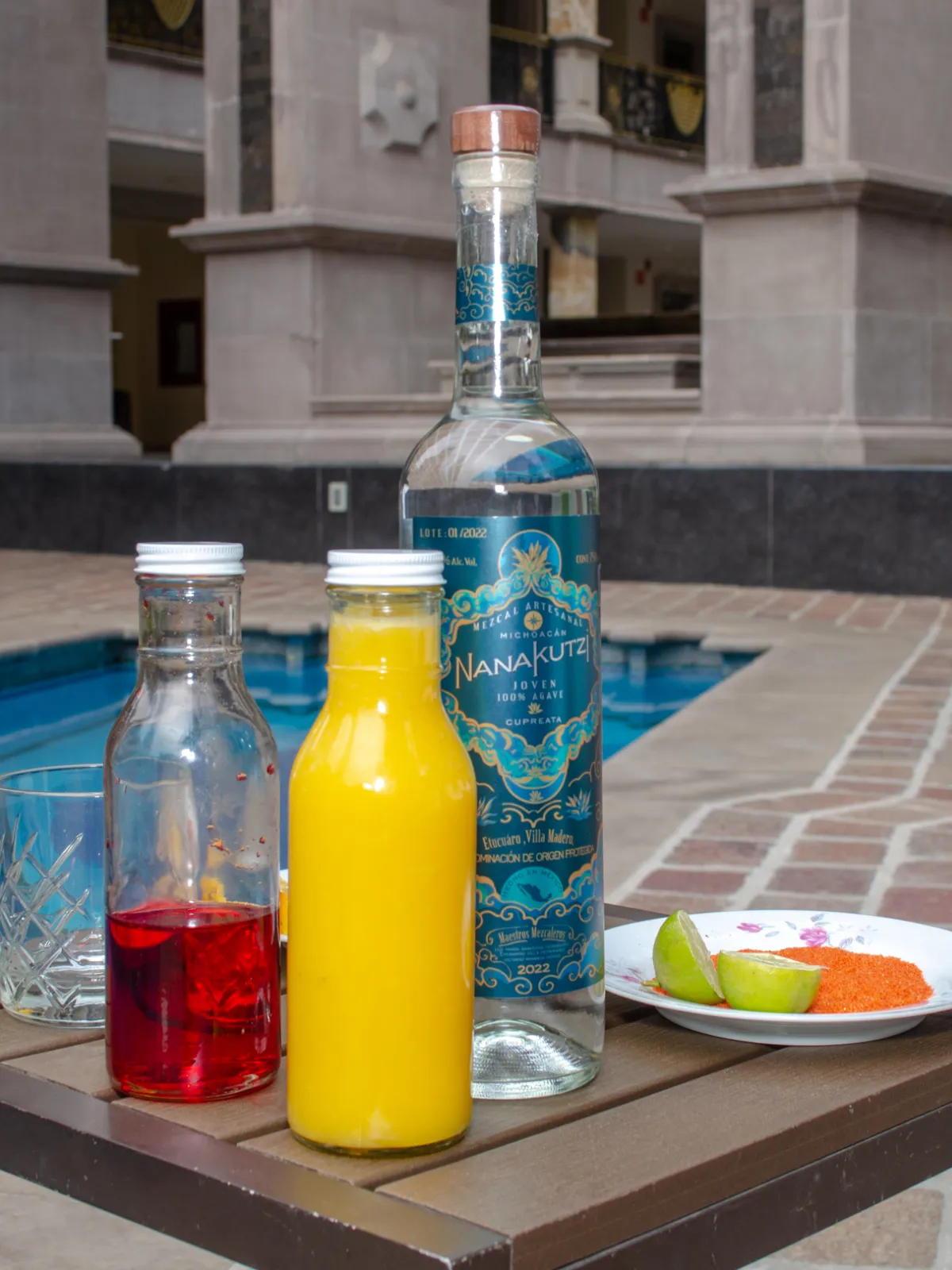 Nanakutzi Mango Fresh RTD styled shot with juices and fruit by courtyard pool