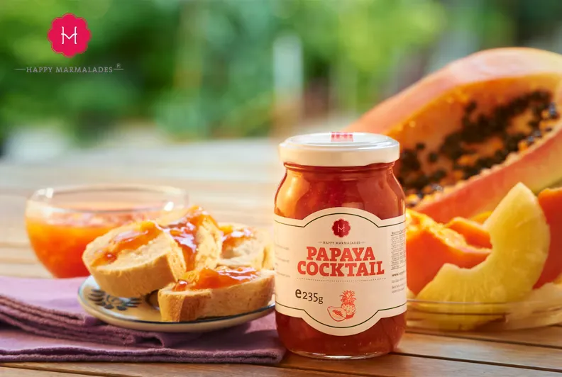 Papaya Cocktail jar with sliced papaya, orange, and bread on woven placemat