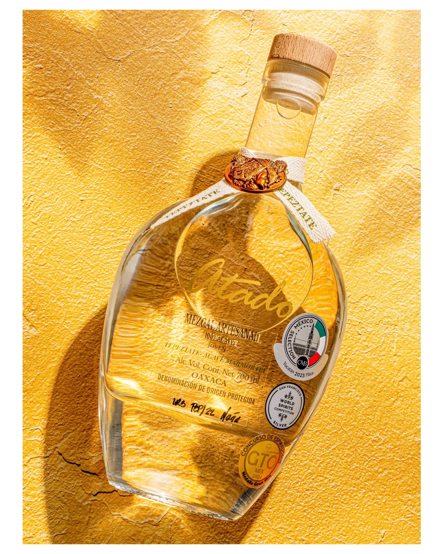 Piztaté bottle casting shadow on yellow textured wall in sunlight