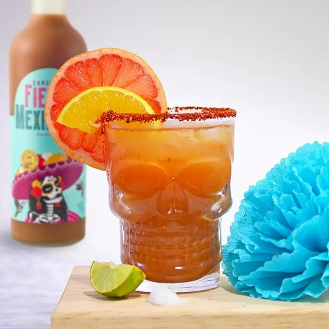 Sangrita cocktail in calavera skull glass with grapefruit and blue paper flower