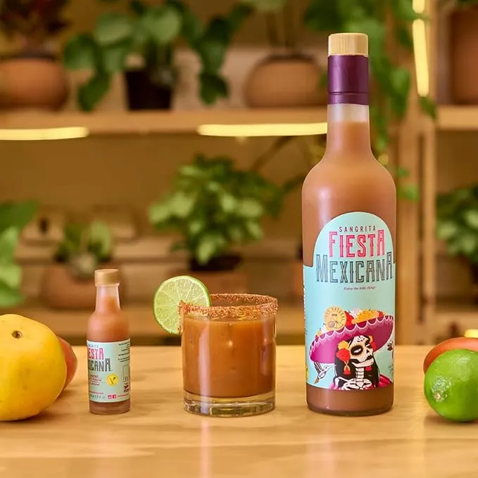 Sangrita 750ml bottle with tomato, orange, and shot glass on blue background