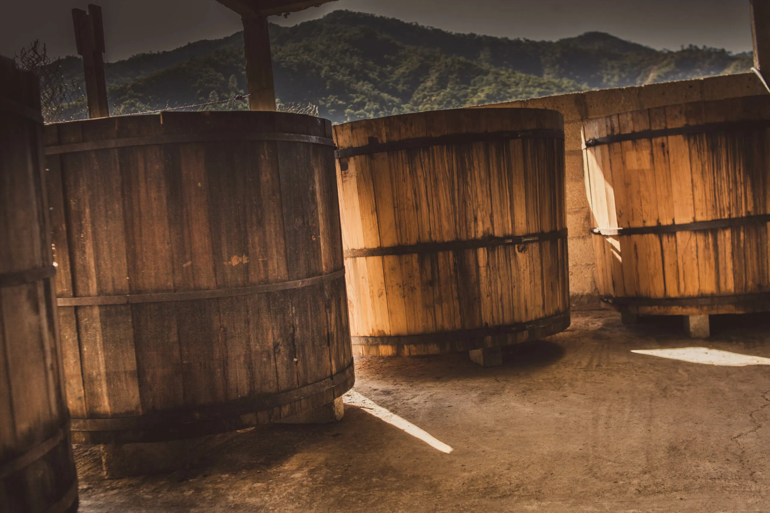 Wooden fermentation vats at palenque with Oaxaca mountains in background